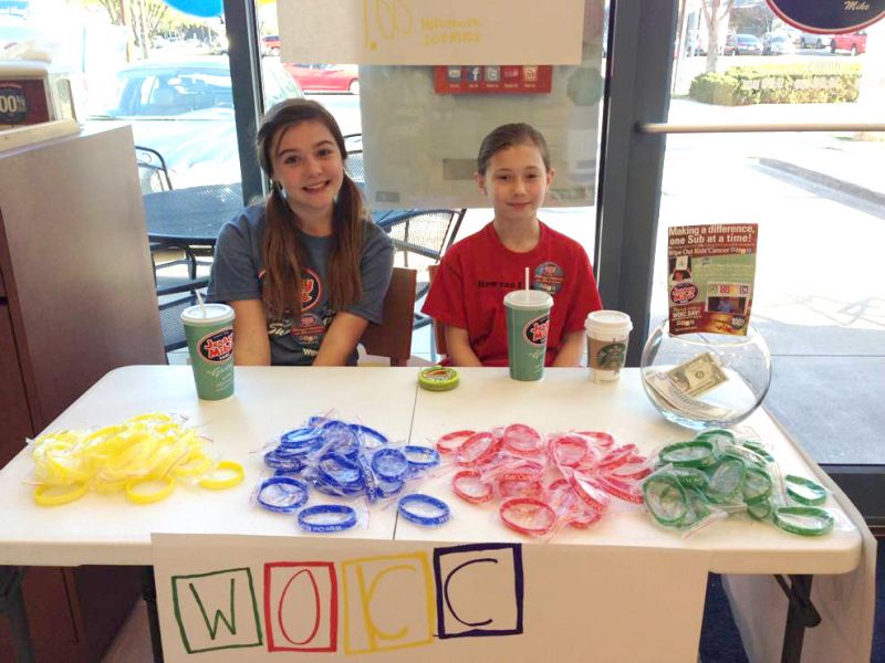 Lily Stewart, area director and franchise owner Dalton Stewart’s daughter, is selling Wipe Out Kids’ Cancer (WOKC) bracelets with Tatum Costolo, daughter of WOKC CEO Evelyn Costolo, on Jersey Mike’s “Day of Giving”. The girls raised $418 for WOKC during the lunch at Jersey Mike’s Subs, 14060 Dallas Parkway, Dallas, TX on March 27, 2013.