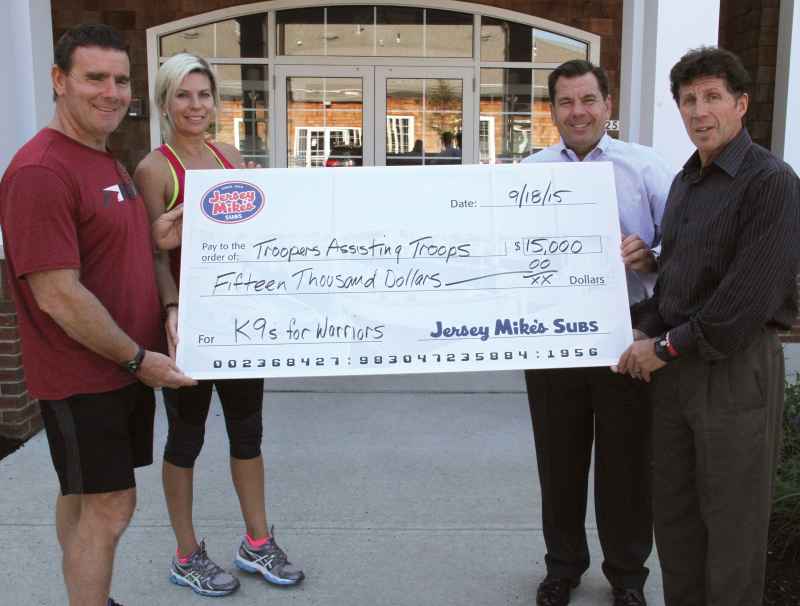 Fresh from a training session at Jersey Mike’s corporate gym, Tatiana Cancro, along with Tom Waldron (l., getdate(), getdate() ), retired state trooper and personal trainer at Jersey Mike’s, Michael Manzo, Jersey Mike’s Subs COO (second from right, getdate(), getdate() ), and Keith Hertling, Jersey Mike’s Vice President of Franchisee Operations (r., getdate(), getdate() ), presented a $15,000 check to Troopers Assisting Troops. The donation supports K9s For Warriors, a service dog program.