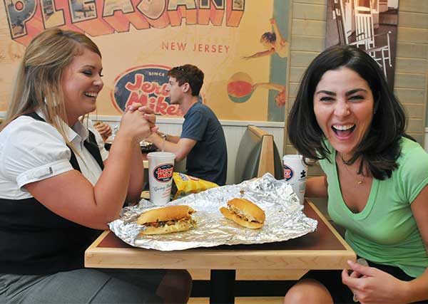 Two customers really enjoying their subs at Jersey Mike's